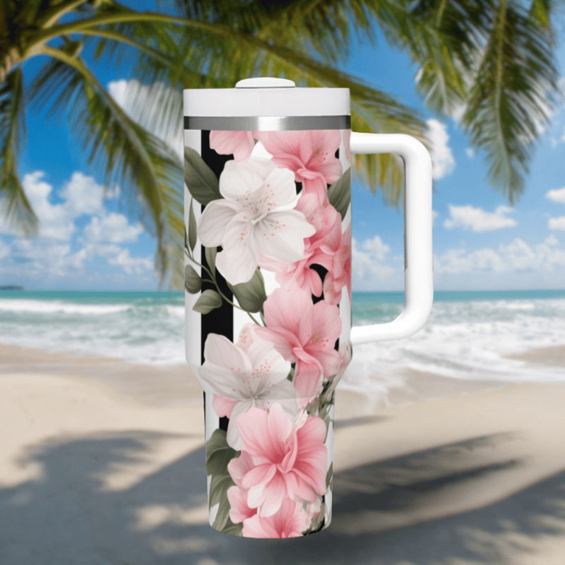 a white and pink flowered coffee mug on a beach
