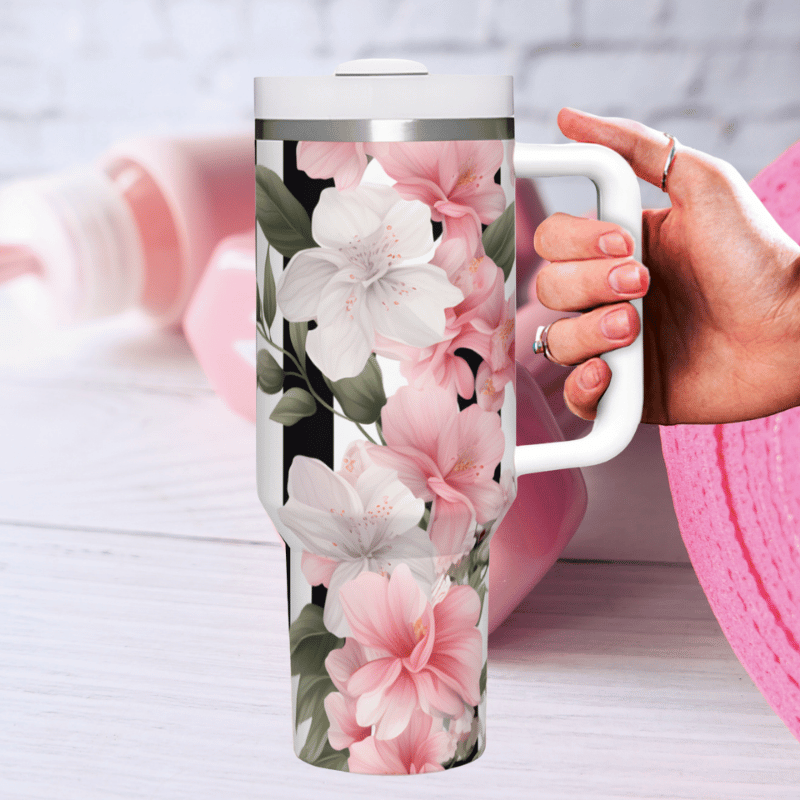 a woman's hand holding a coffee cup next to a pink hat