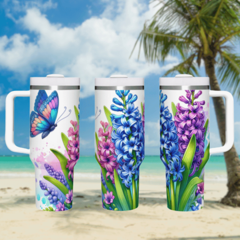 three travel mugs on a sandy beach with a palm tree in the background